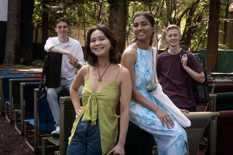 A group of students with 2 males and 2 females posing at an outdoor cinema looking directly at the camera.
